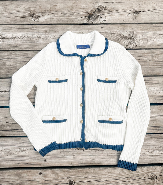 White ribbed sweater with blue trim on a wooden surface