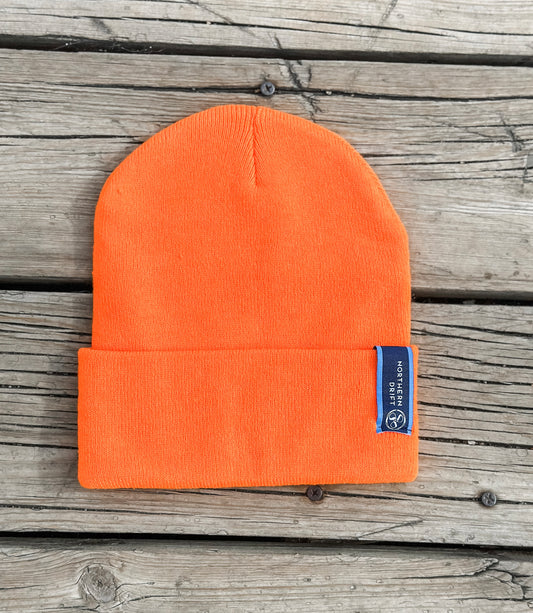 Orange beanie with a blue label on a wooden surface